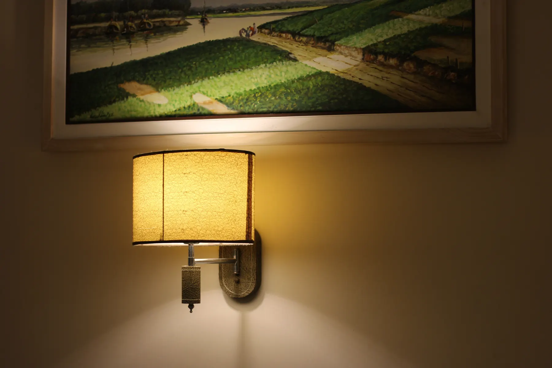 Warm painted interior wall with a shaded sconce and framed artwork